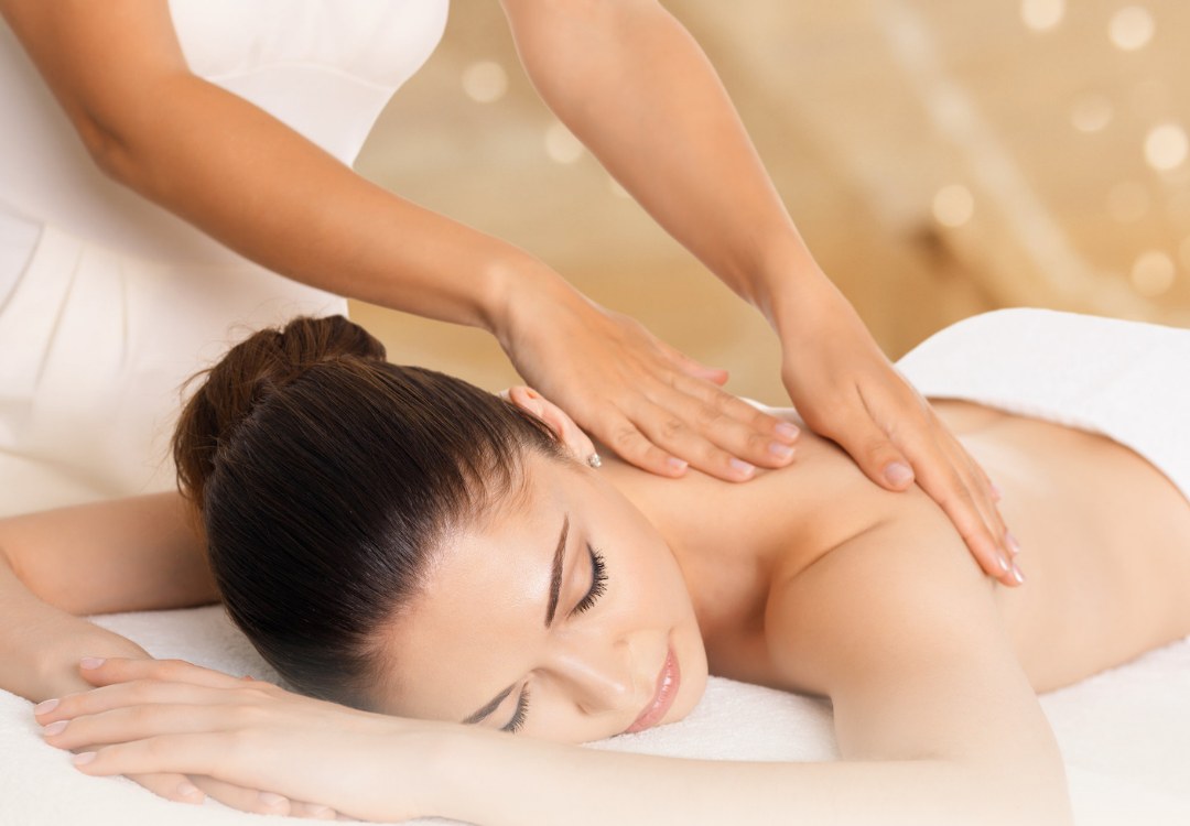 Hands working on a client's shoulders during a massage