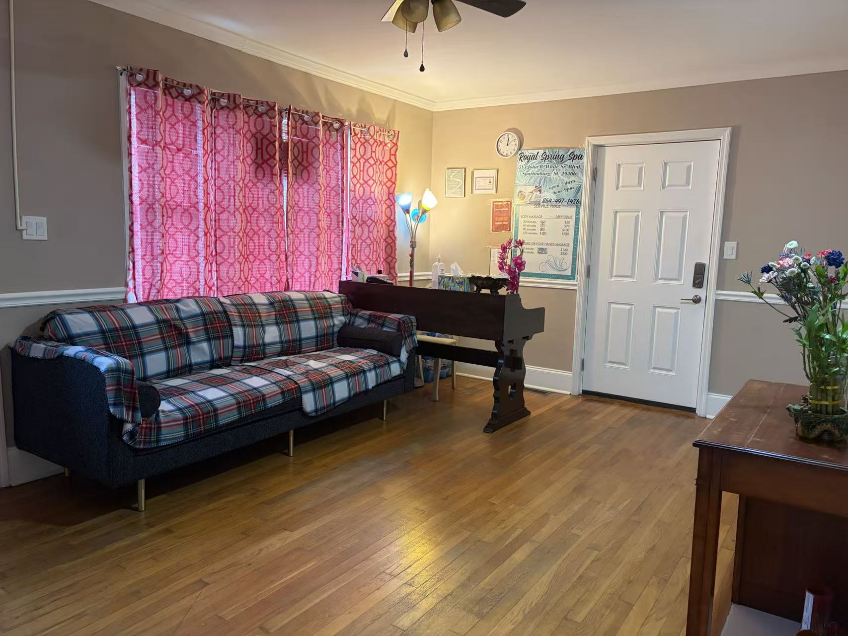 Our front room with a sofa, a service price board and the entrance door